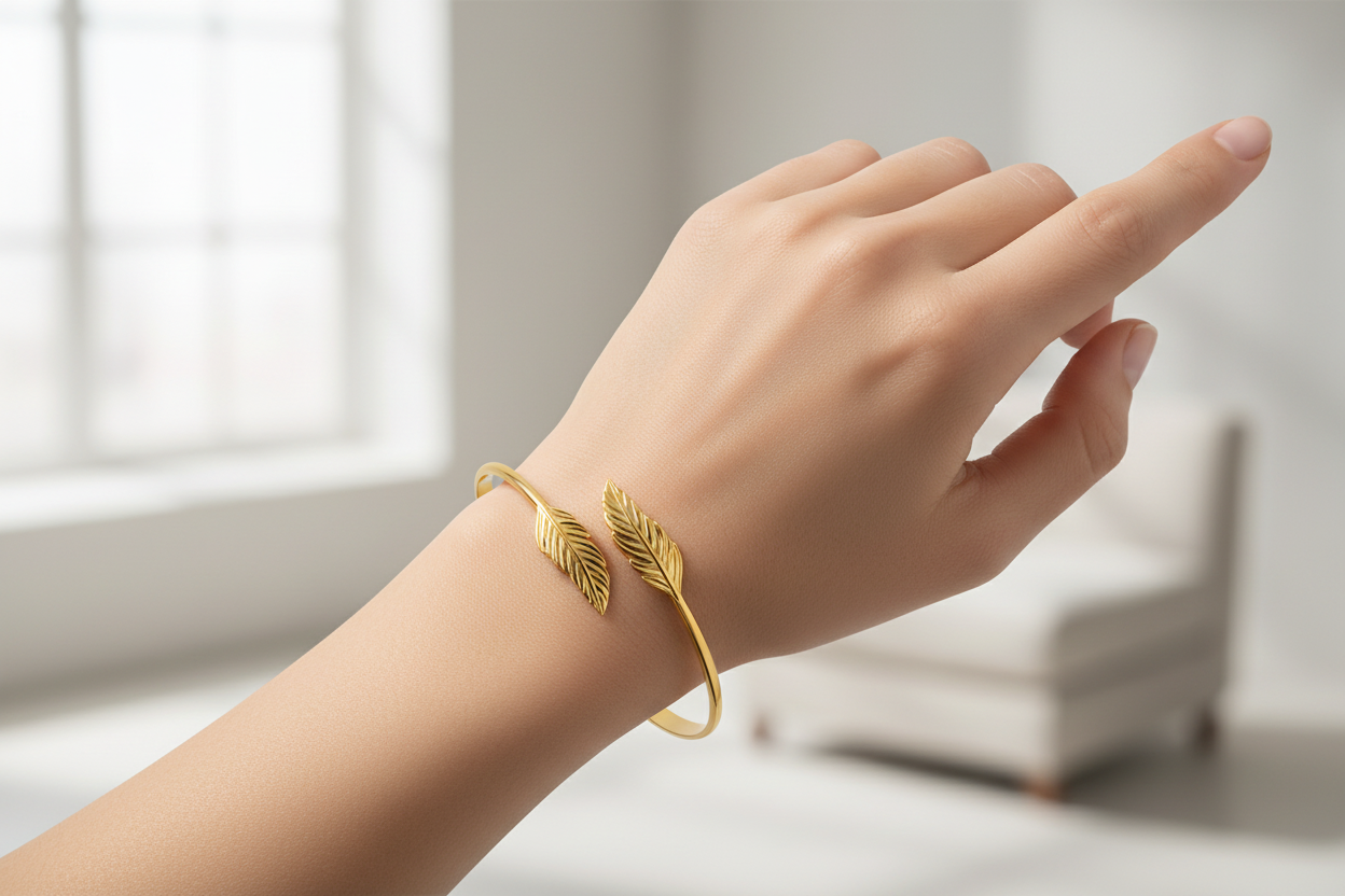 Gold plated leaf bracelet on a hand with a blurred indoor background