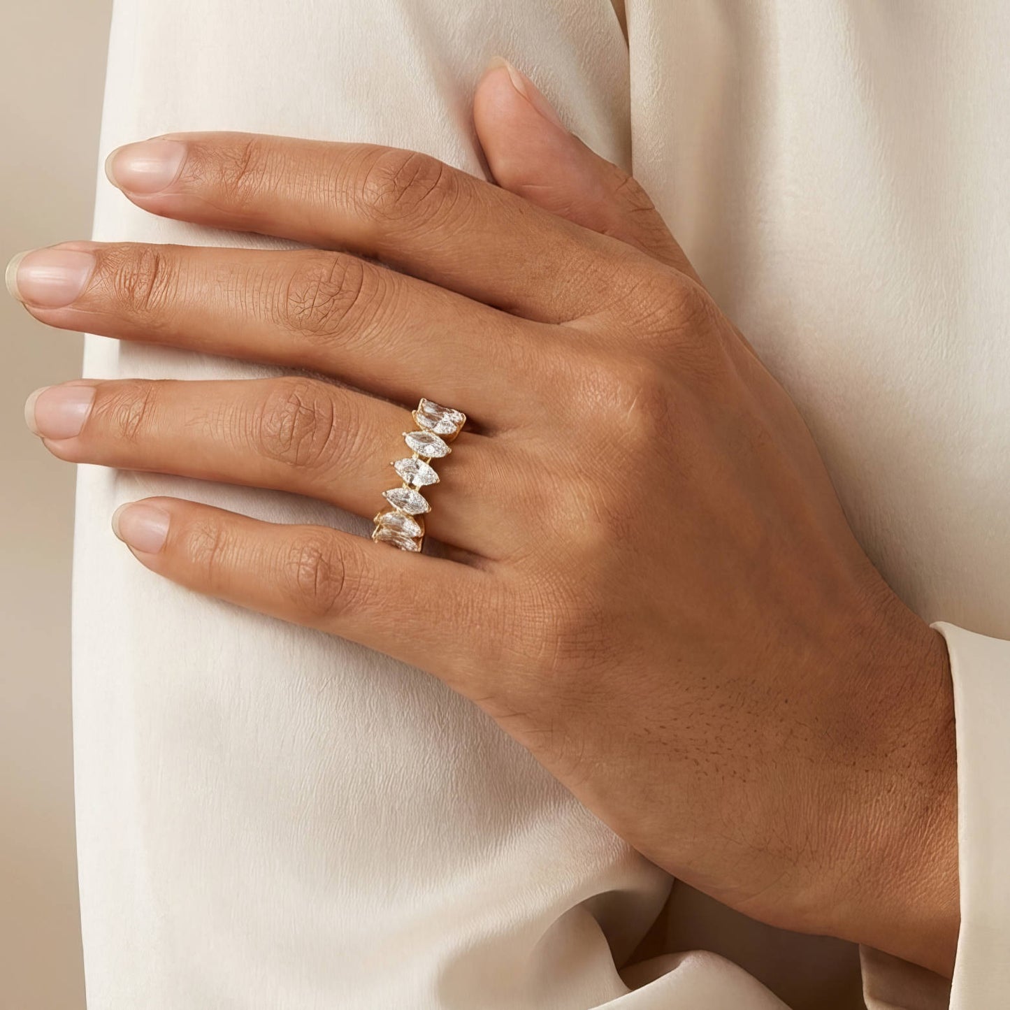 Hand wearing a diamond ring on a light fabric background