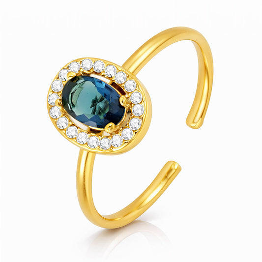 Gold ring with a blue gemstone and clear stones on a white background