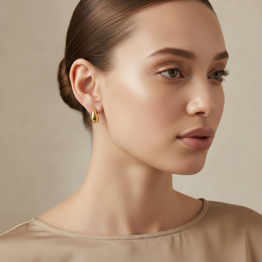 Woman wearing gold earrings against a neutral background