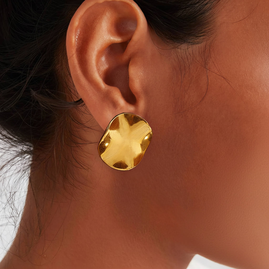 Gold earring worn by a person with a neutral background