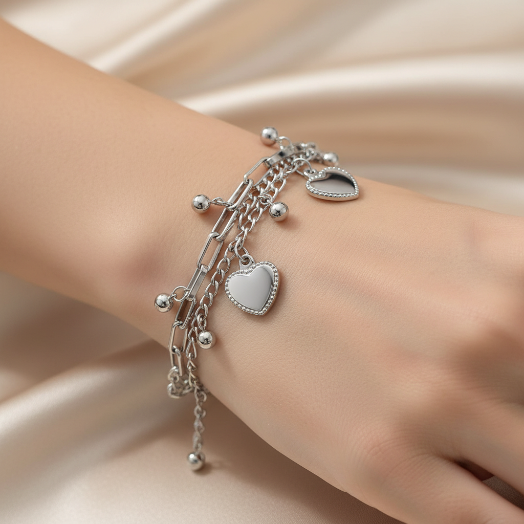 Silver bracelet with heart charms on a wrist against a beige fabric background