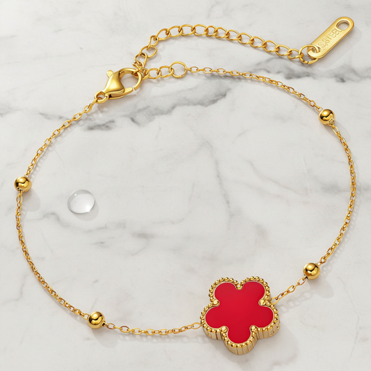 anti Tarnish Gold plated bracelet with a red clover-shaped charm on a marble background