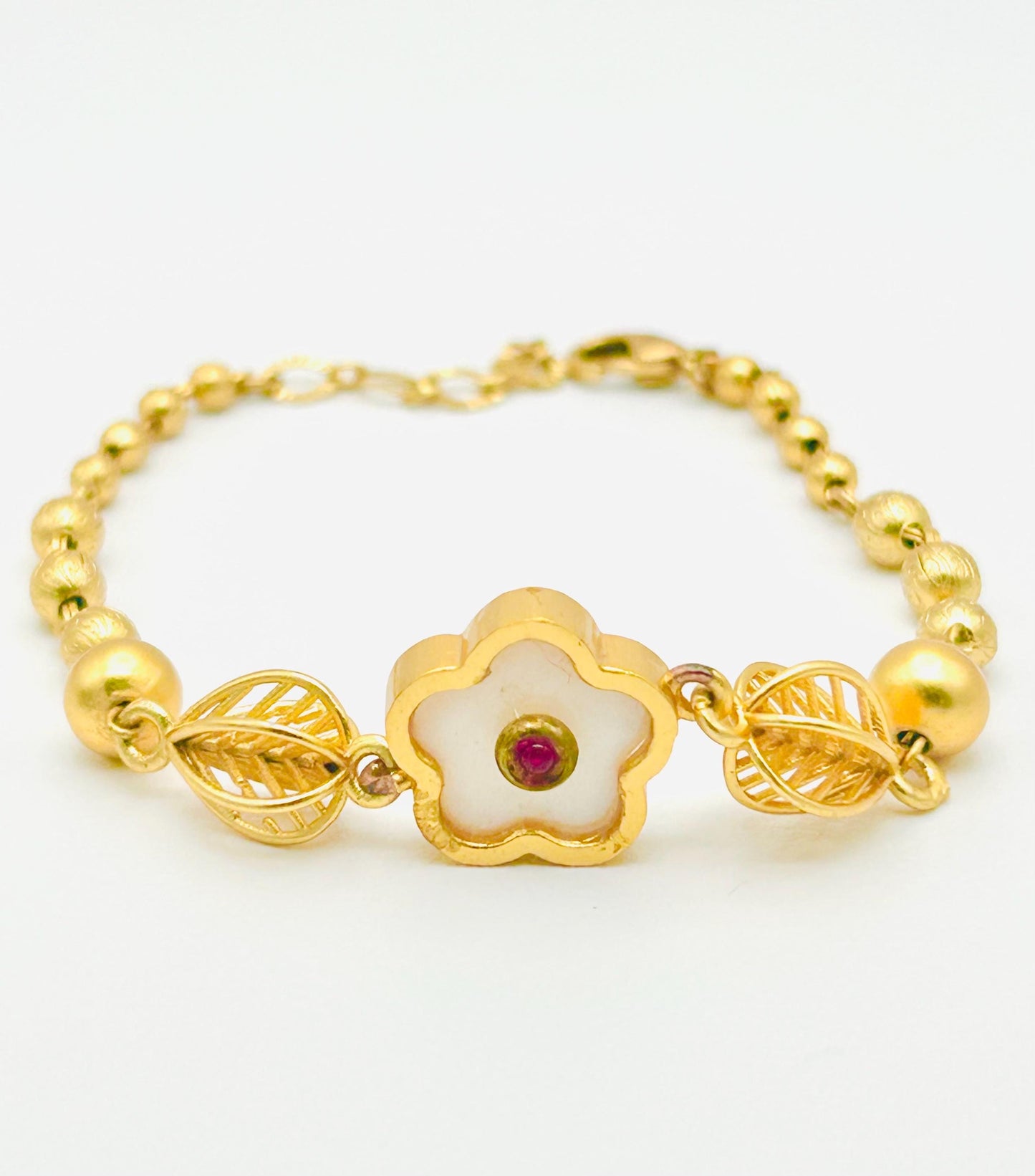 Gold bracelet with a floral clasp on a white background