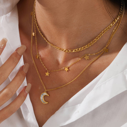 Close-up of a person wearing 18k gold plated necklaces with star and moon pendants.