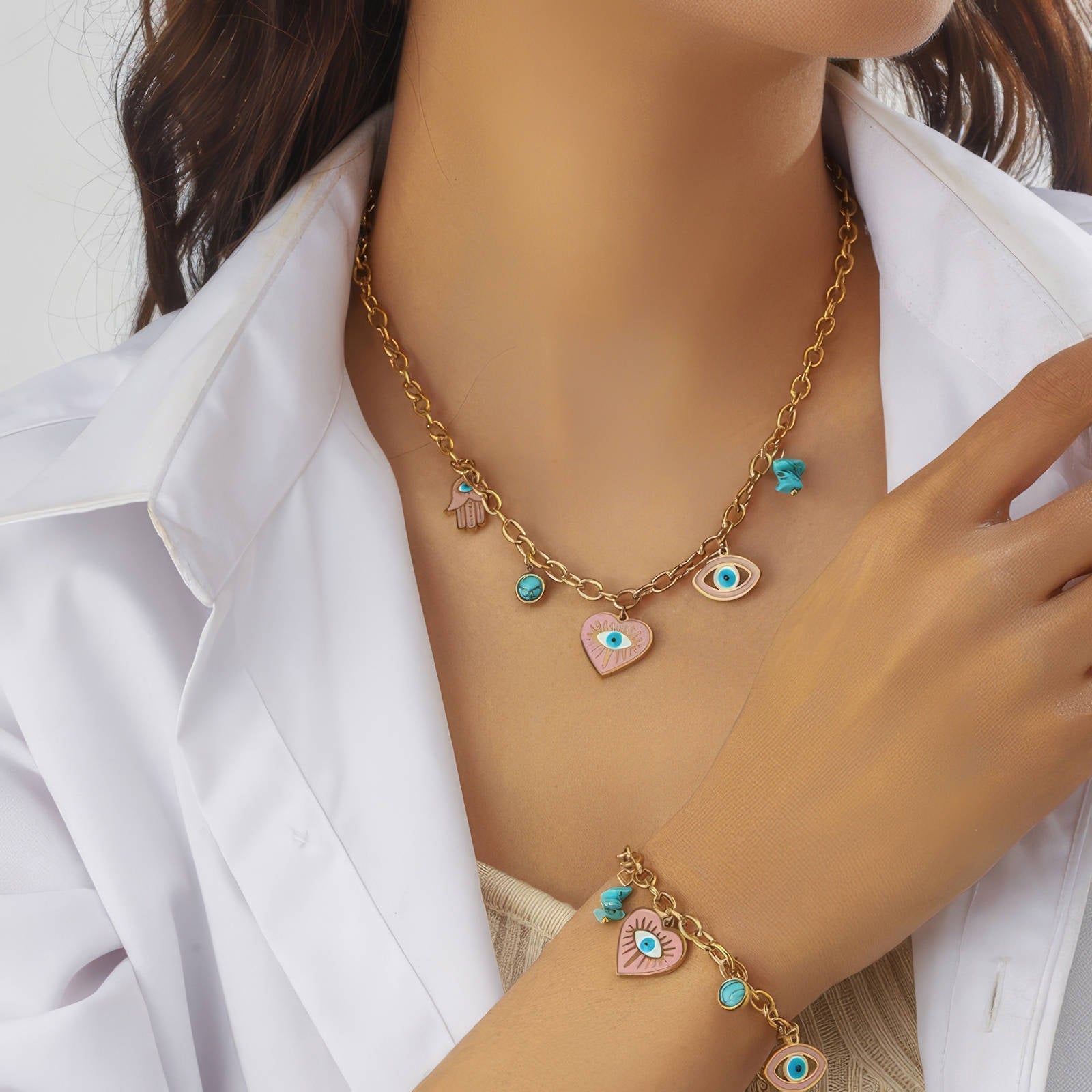 anti tarnish 18k plated gold Necklace and bracelet with heart and eye charms on a person wearing a white shirt.