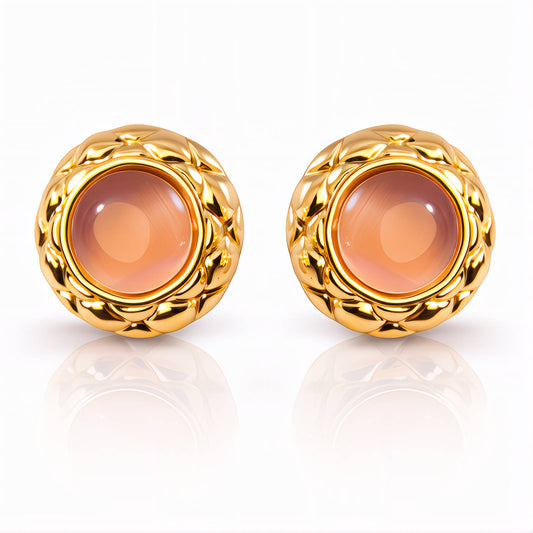 Pair of gold earrings with a central peach-colored gemstone on a white background