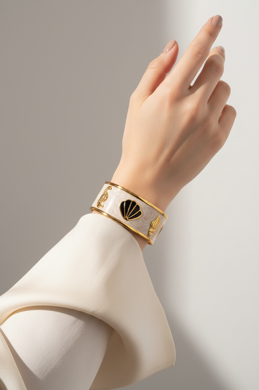 Hand wearing a gold and white bracelet against a neutral background