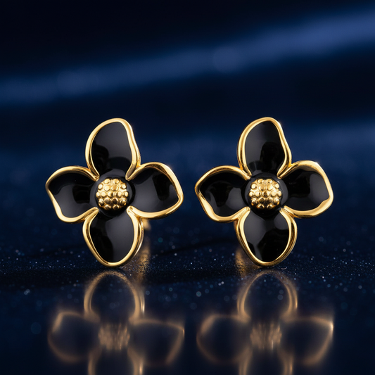 Pair of black and gold flower-shaped earrings on a reflective dark surface.