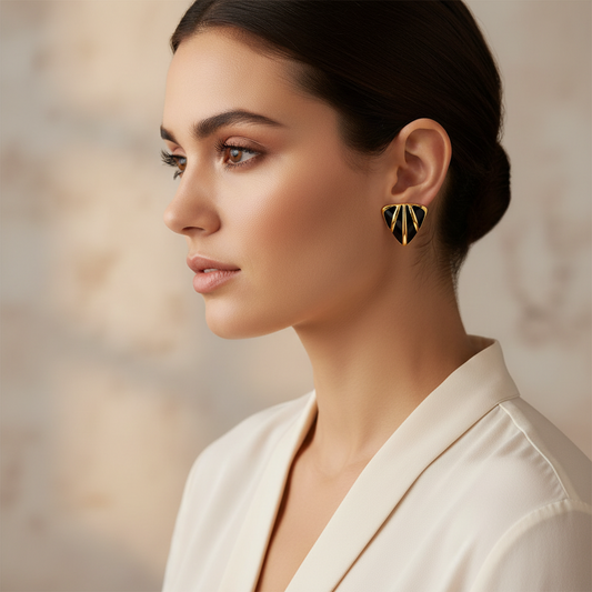 Woman wearing gold and black geometric earrings against a neutral background