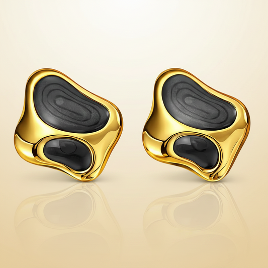 Gold and black earrings on a beige background