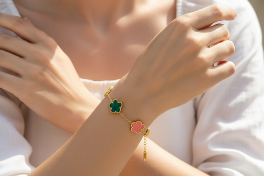 Close-up of a hand wearing a bracelet with a colorful flower charm on a light background