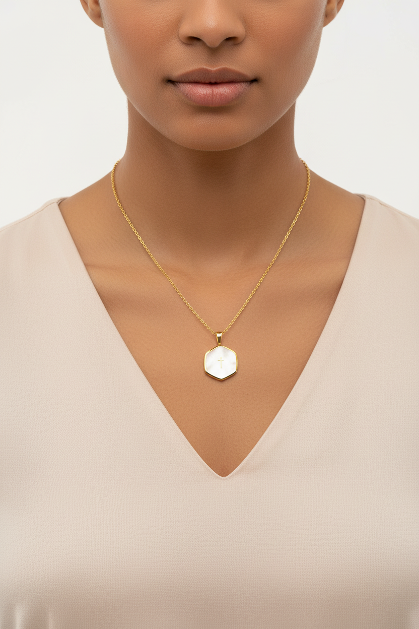 Woman wearing a gold necklace with a hexagonal pendant on a plain background