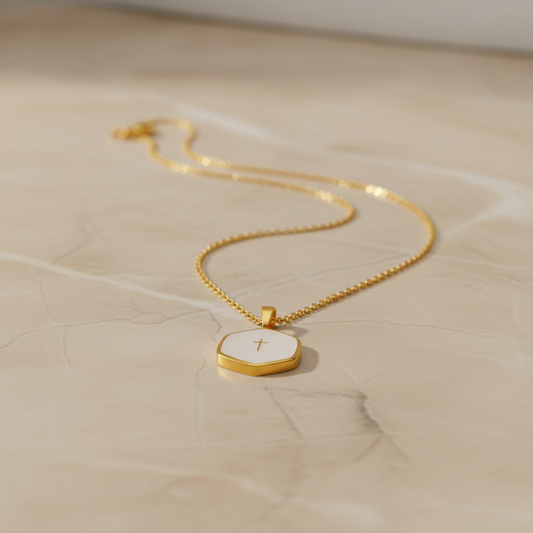 Gold necklace with a pendant on a beige surface