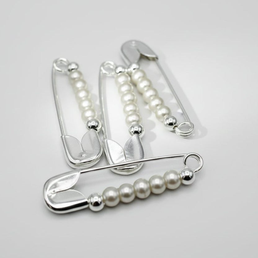 Silver safety pins with beads on a gray background
