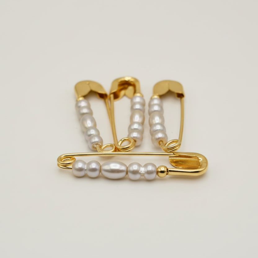 safty pins with pearls on a light gray background