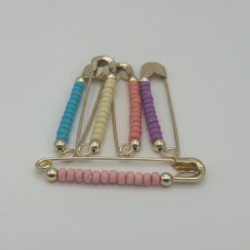 Decorative safty pins with colorful beads on a white background
