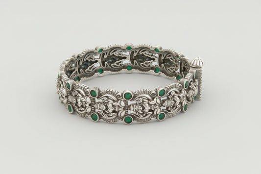 Decorative Oxidized silver bracelet kada with green gemstones on a wooden surface