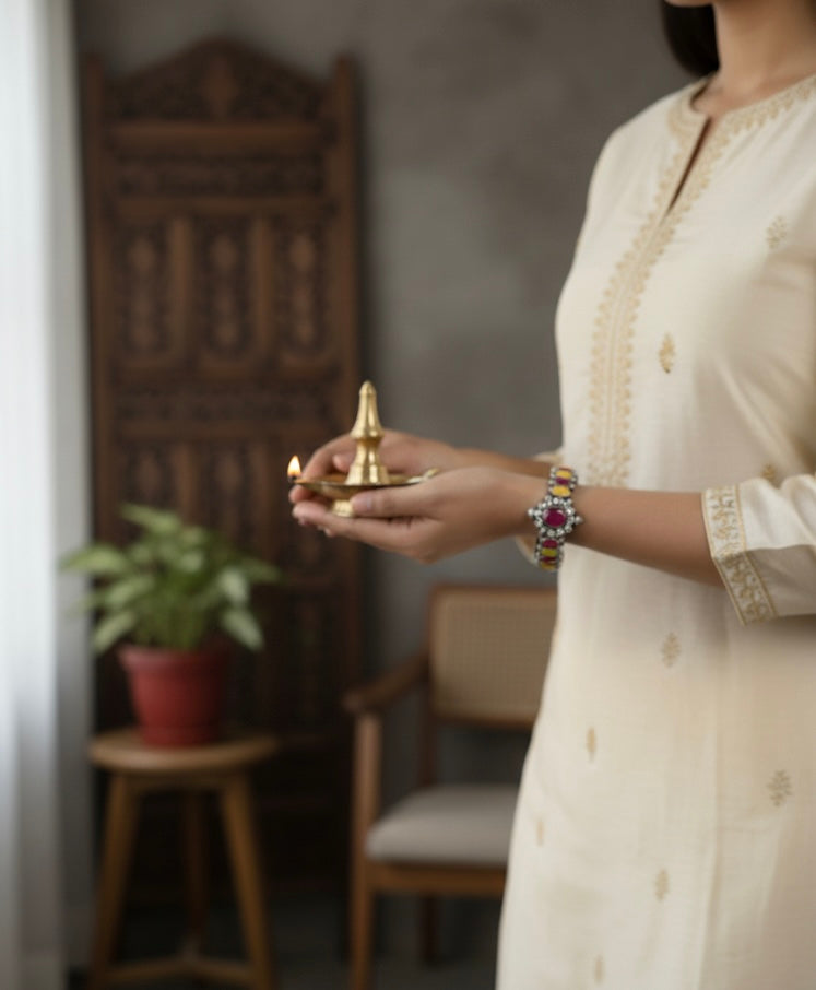Person holding a small brass lamp indoors with a blurred background