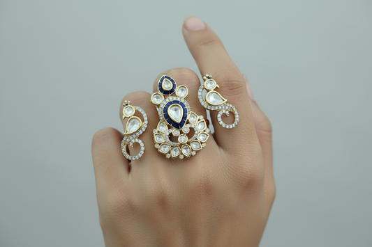 Hand wearing three ornate two finger ring rings with intricate designs on a gray background