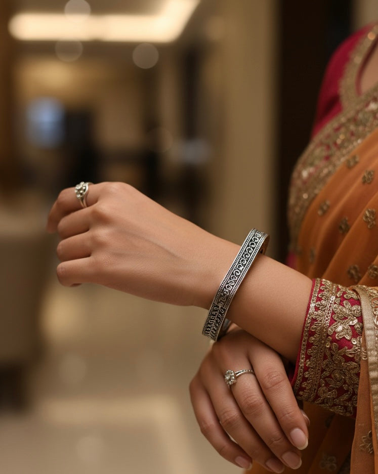 Close-up of a hand wearing a silver bracelet and ring with a blurred background