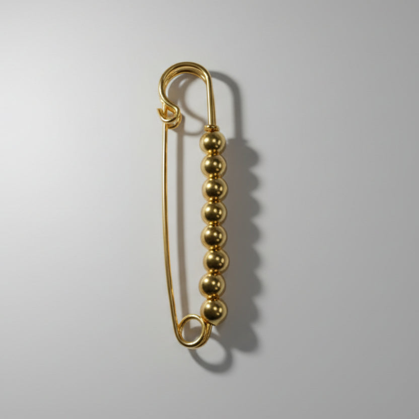 Gold safety pin on a gray background