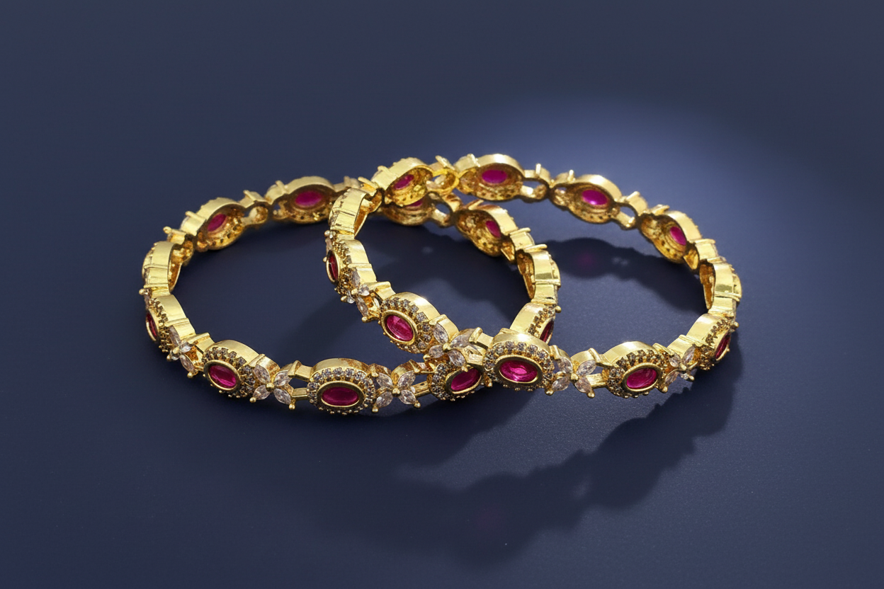Gold bangles with red gemstones on a dark blue background