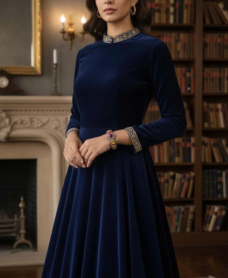 Woman in a dark blue dress with decorative elements in a room with a fireplace and bookshelf.