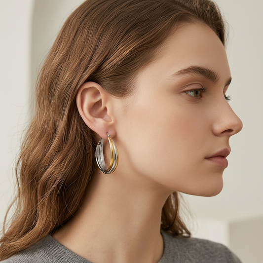 Close-up of a woman wearing gold hoop earrings with a neutral background