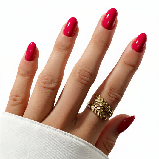 Hand with bright pink nails and a gold leaf ring on a white background