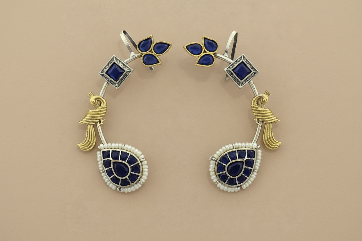 Pair of earrings with blue gemstones and gold accents on a beige background