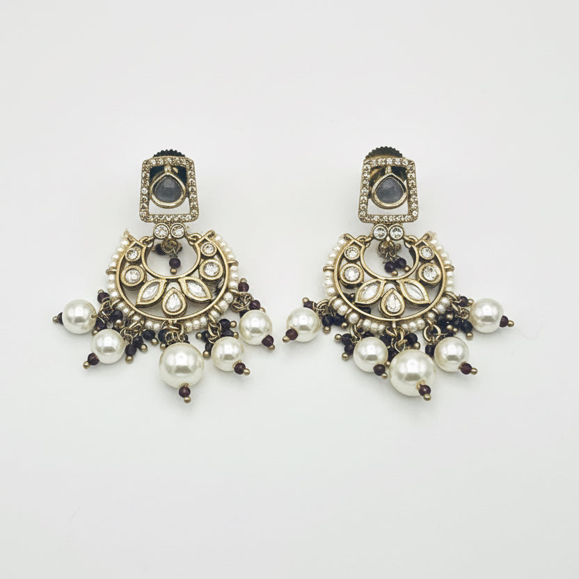 Pair of ornate earrings with pearls on a white background