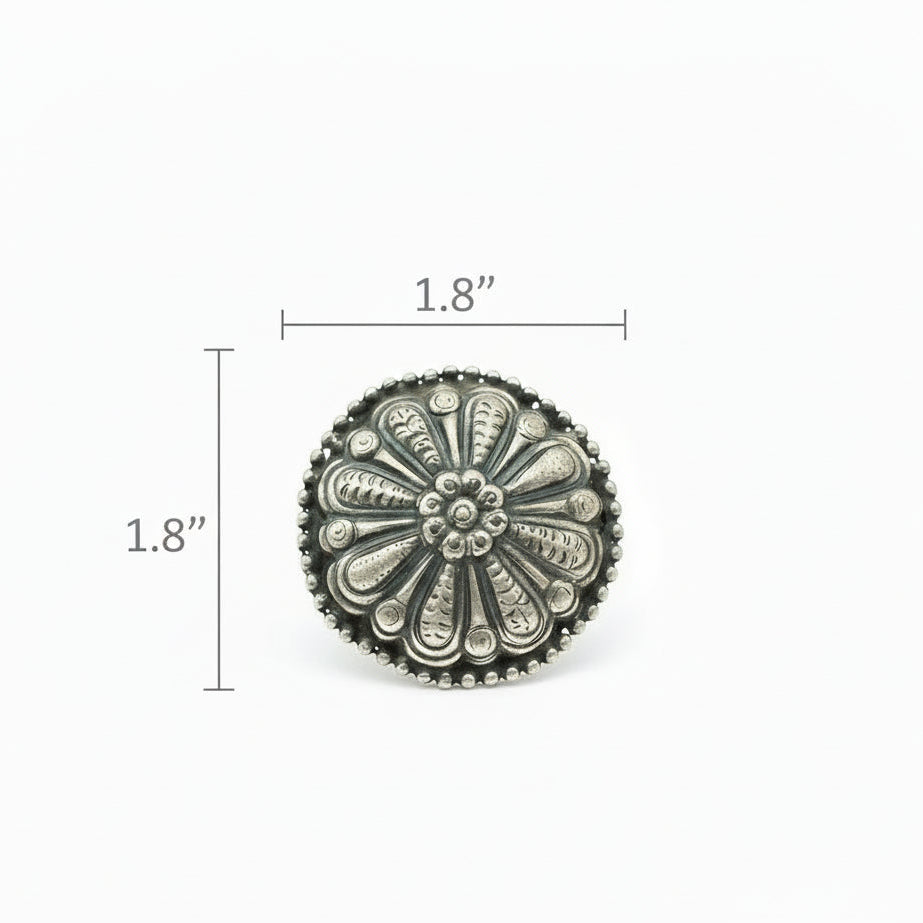 Decorative silver button with intricate design on a white background