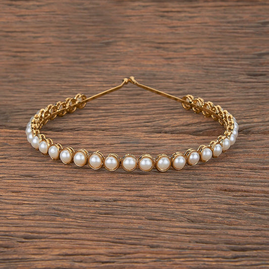 Gold headband with pearls on a wooden surface