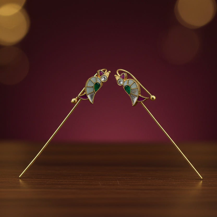 Pair of gold needle ear cuff earrings with gemstones on a light gray background