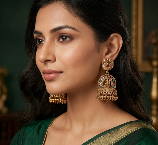 Woman wearing traditional gold earrings with a green saree against a dark background