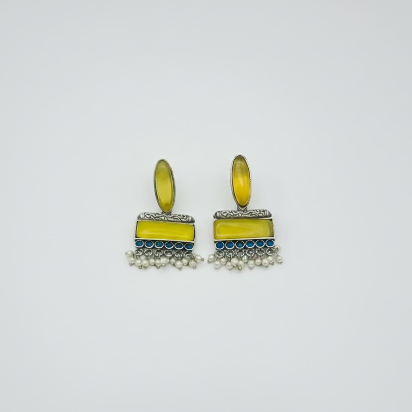 Pair of yellow earrings with blue accents on a light gray background