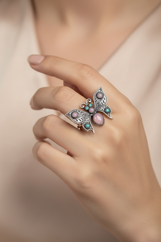 Close-up of a hand wearing an ornate ring with gemstones on a soft background