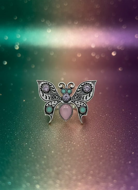 Butterfly-shaped brooch with pink and green accents on a white background