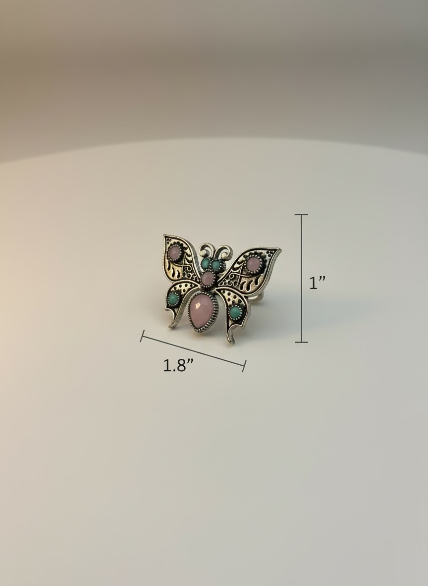 Butterfly-shaped ring with pink and green accents on a white background