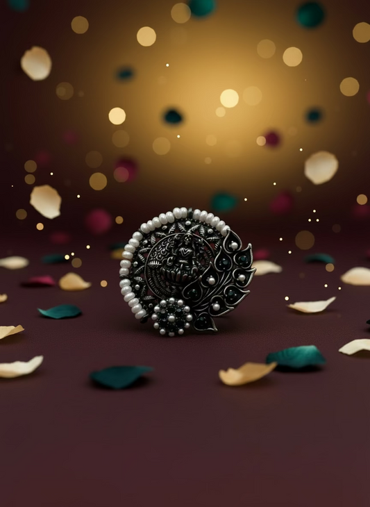 Decorative ring with black and silver design and pearls on a light gray background