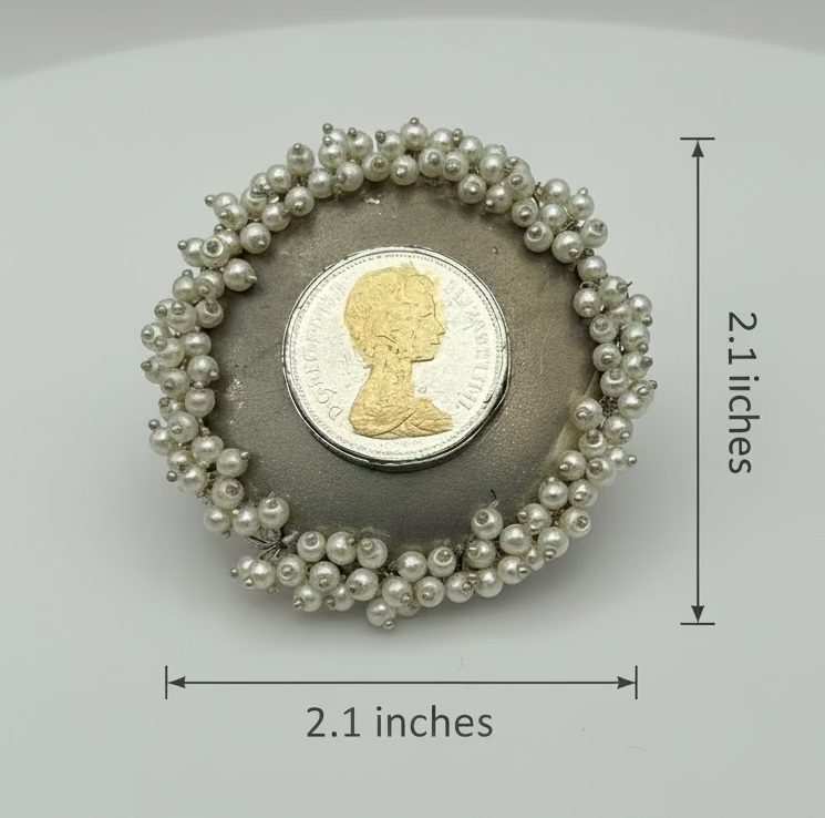 Brooch with pearl-like beads and a coin featuring a portrait on a gray background