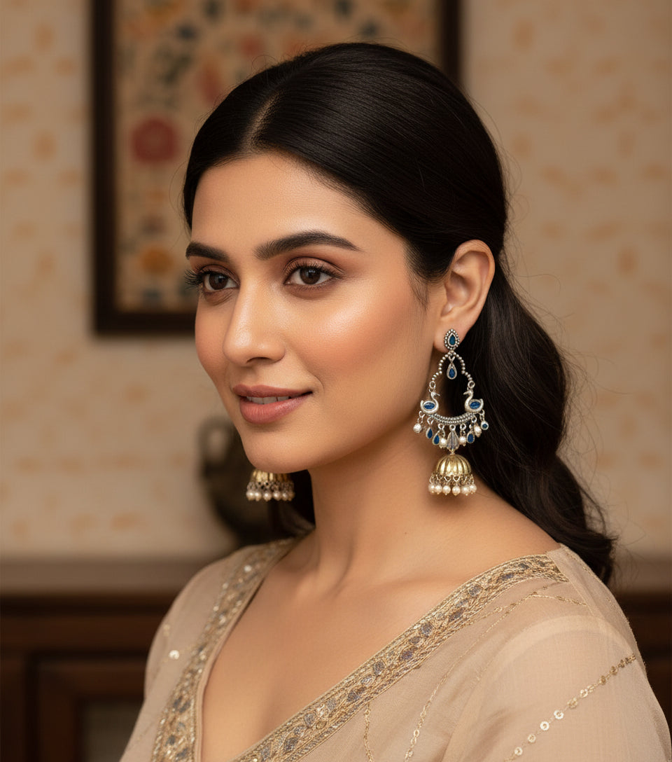Pair of silver earrings with blue stones and pearl-like beads on a white background