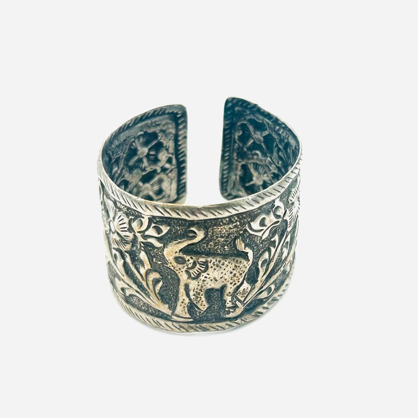 Silver cuff bracelet with intricate designs on a white background