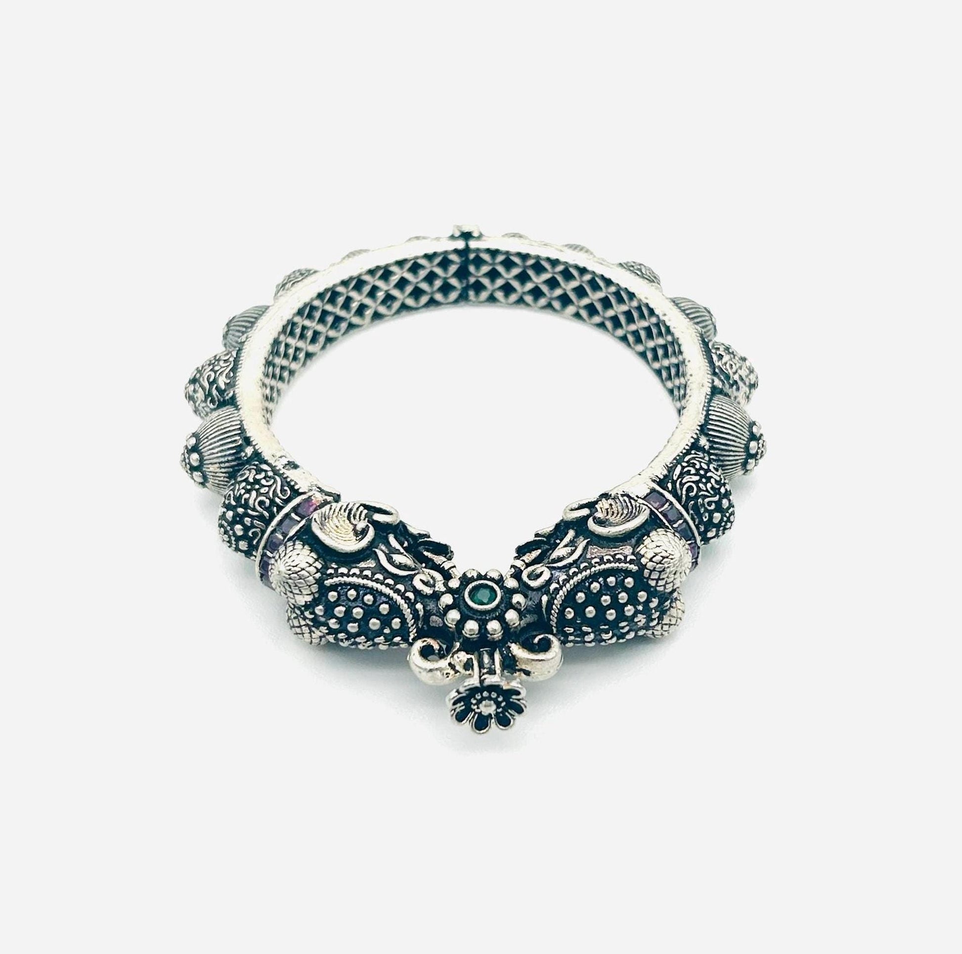 Decorative silver bracelet with intricate designs on a white background