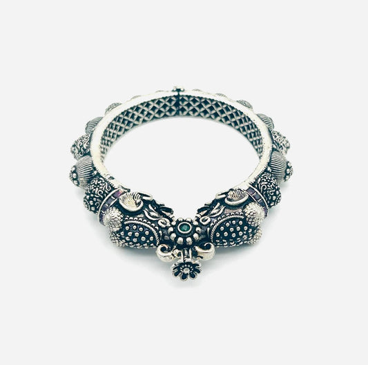 Decorative silver bracelet with intricate designs on a white background