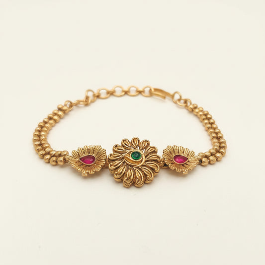 Gold bracelet with floral designs and gemstones on a white background