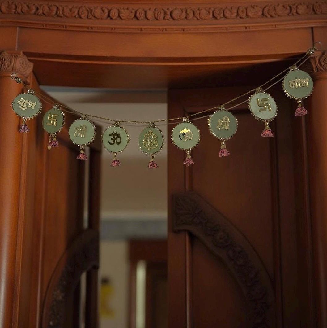 Decorative string with green and gold symbols hanging on a wooden door.