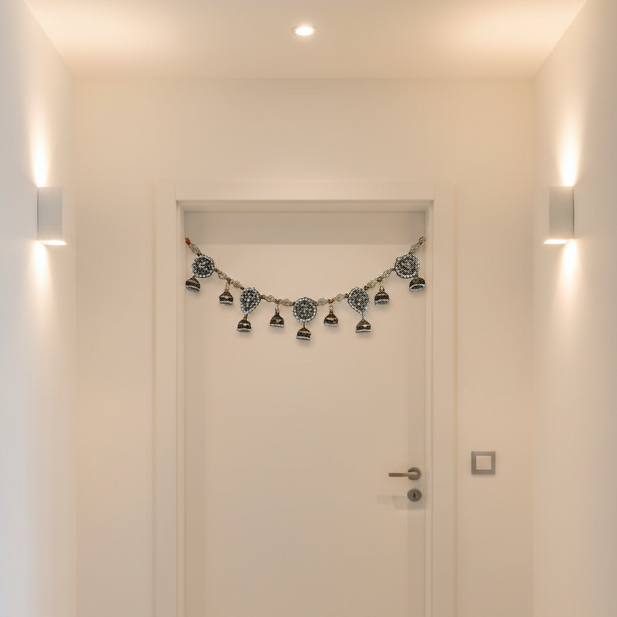Decorative toran hangging string of lights hanging above a closed door in a well-lit hallway.