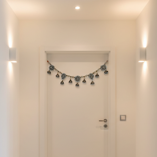 Decorative toran hangging string of lights hanging above a closed door in a well-lit hallway.